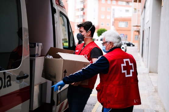 Personal de Cruz Roja introducen en una furgoneta la aportación para atender a personas vulnerables.
